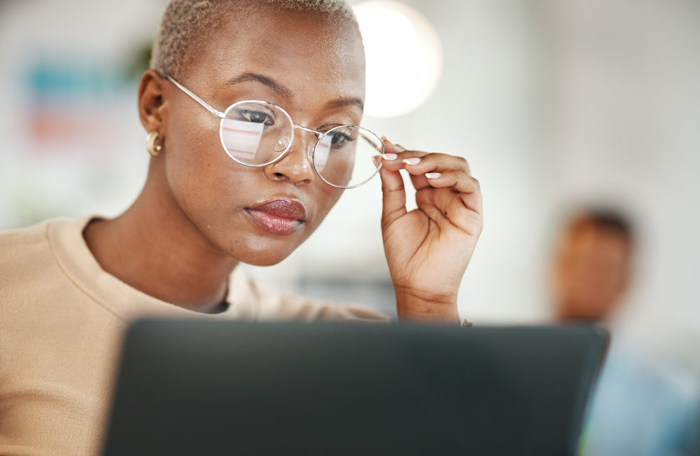 A close up of a young woman at work looking at her laptop, concentrating on a task