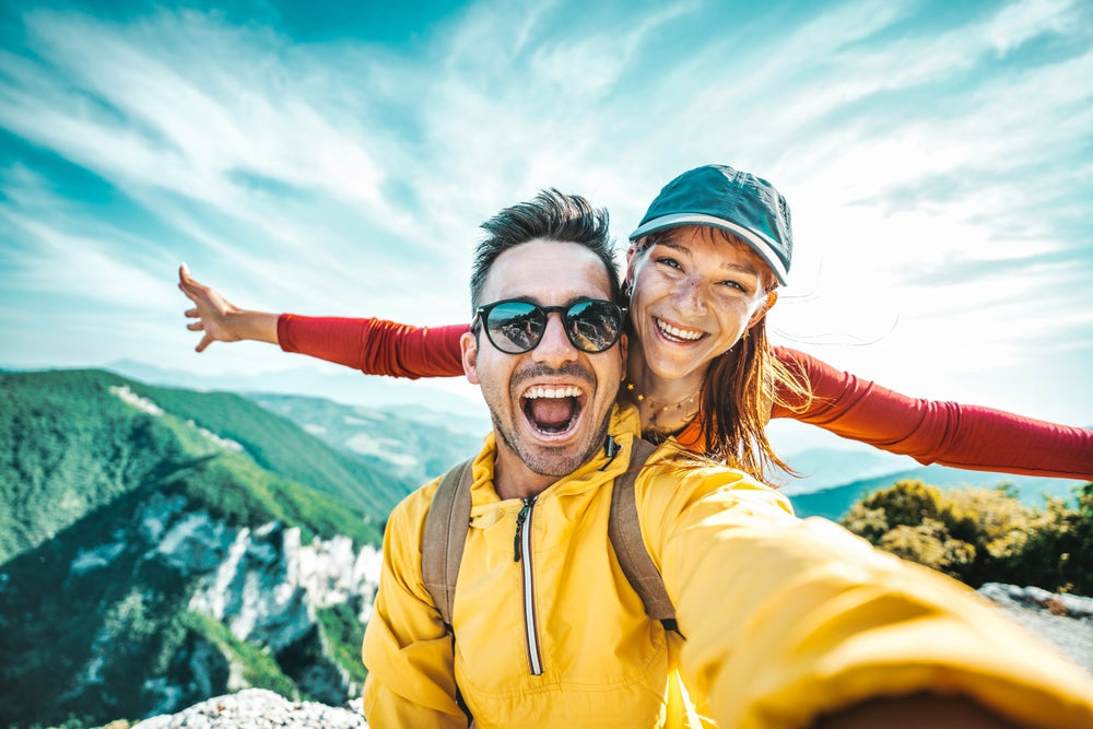 Close up of a happy young couple at the top of a mountain enjoying an exciting summer adventure.