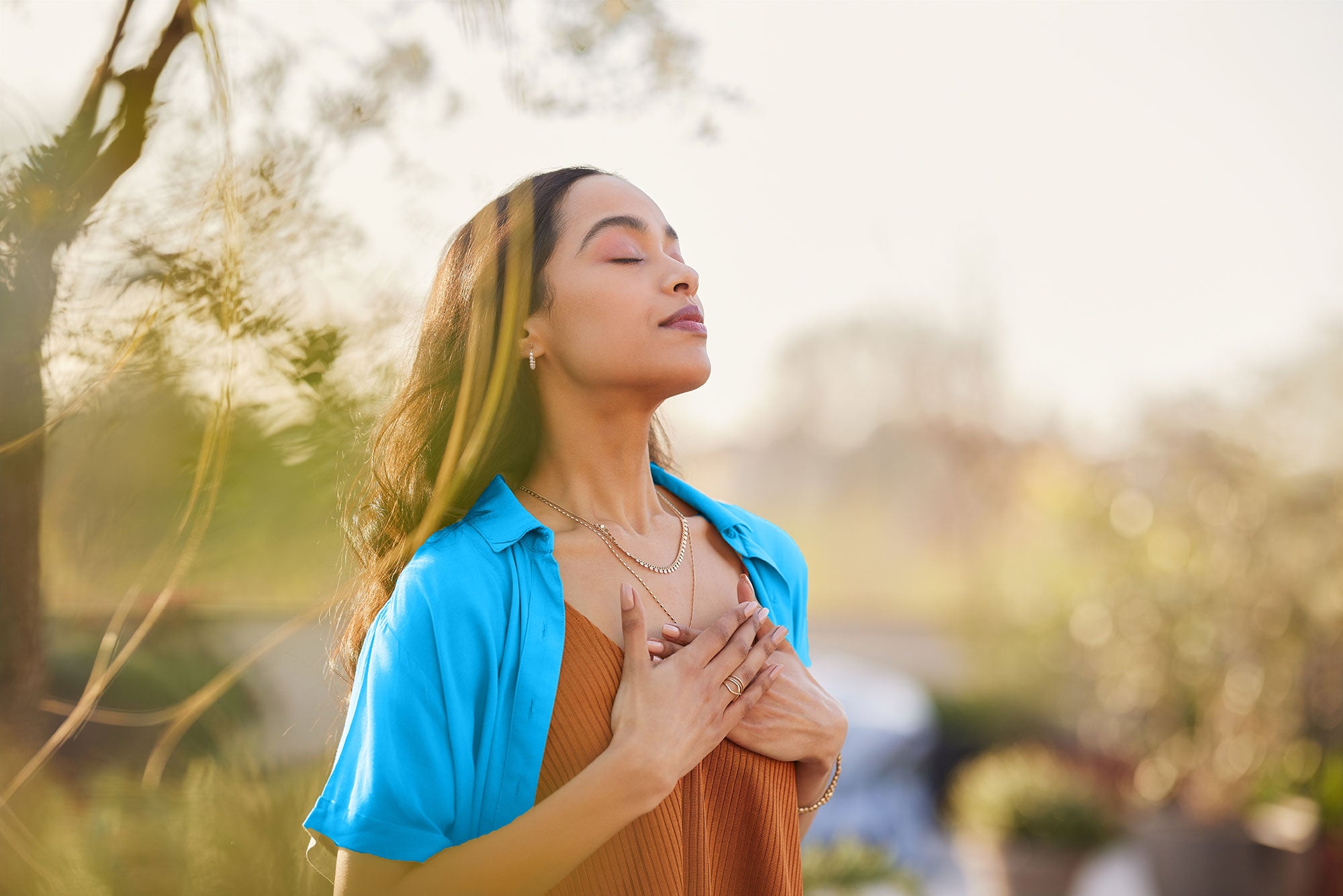 Woman in a blue shirt standing outdoors with a blurred background