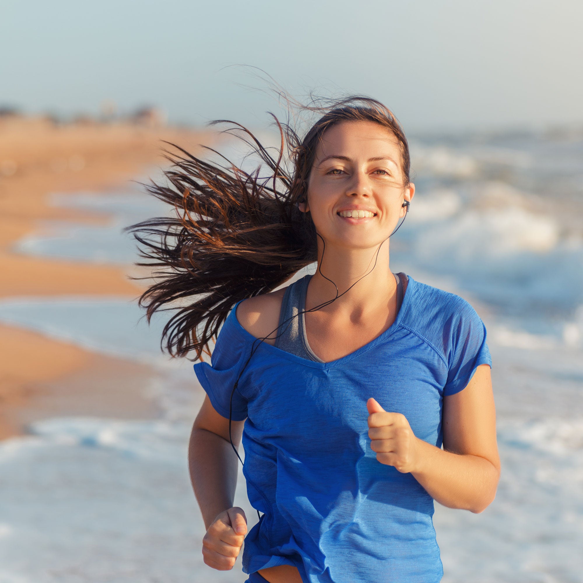 Woman running on a beach with ocean waves in the background