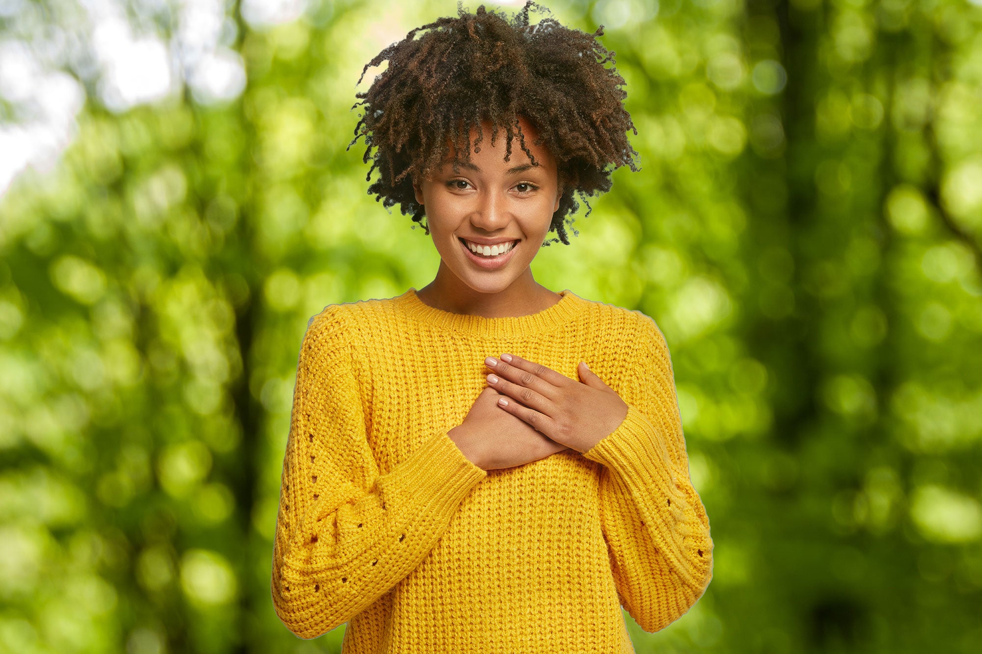 Woman wearing a yellow sweater standing in a forest