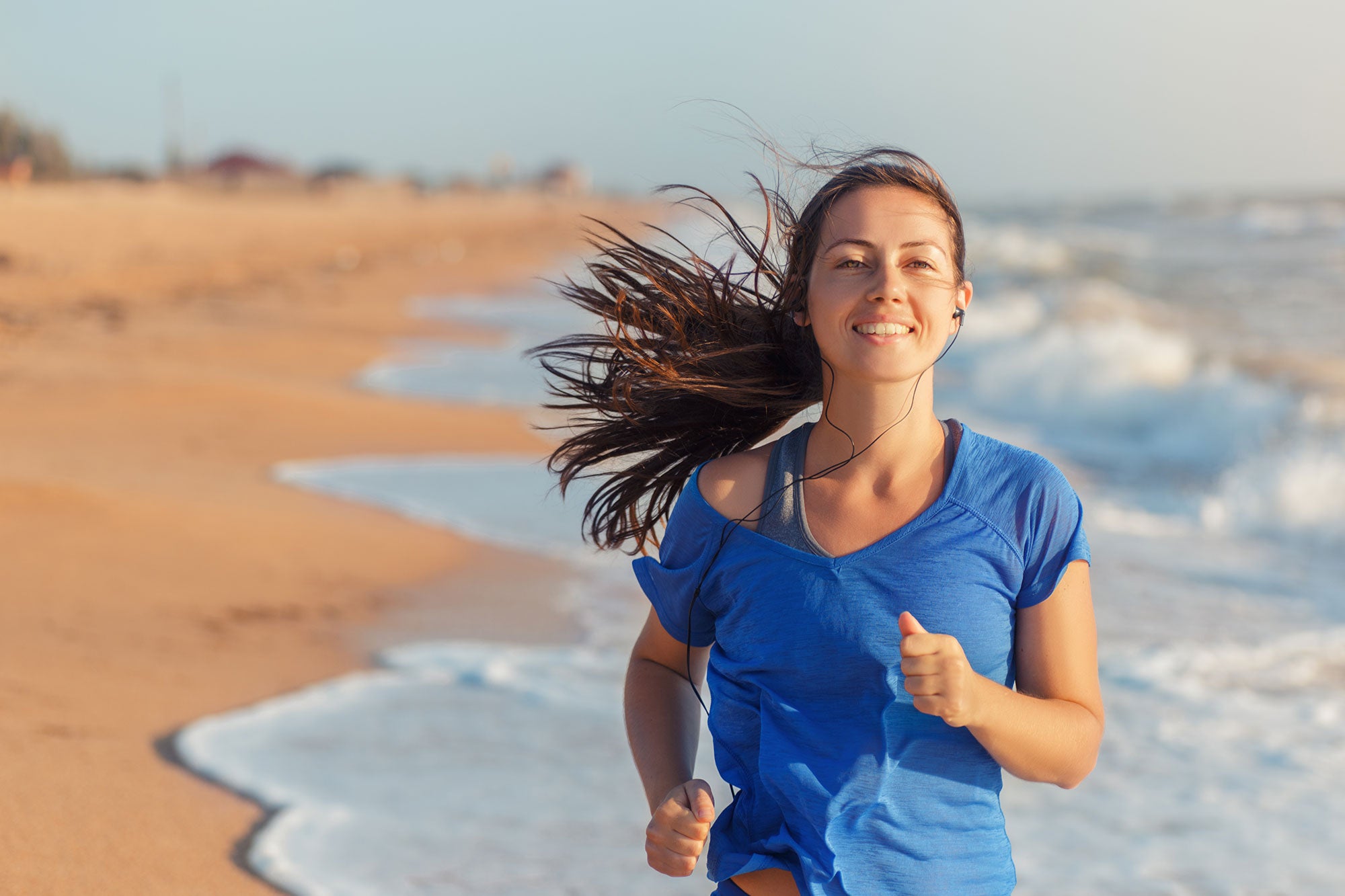 Woman running on a beach with waves and sand in the background