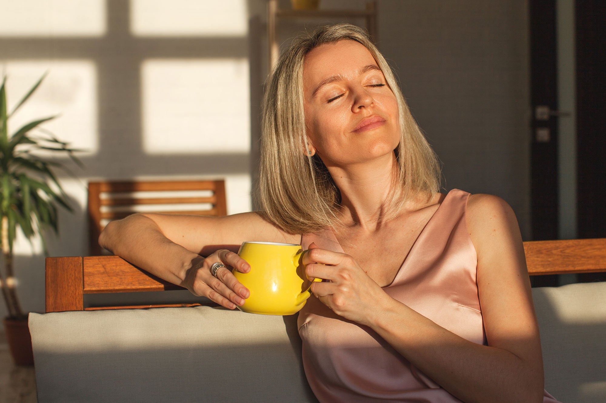 Woman holding a yellow mug in a sunlit room
