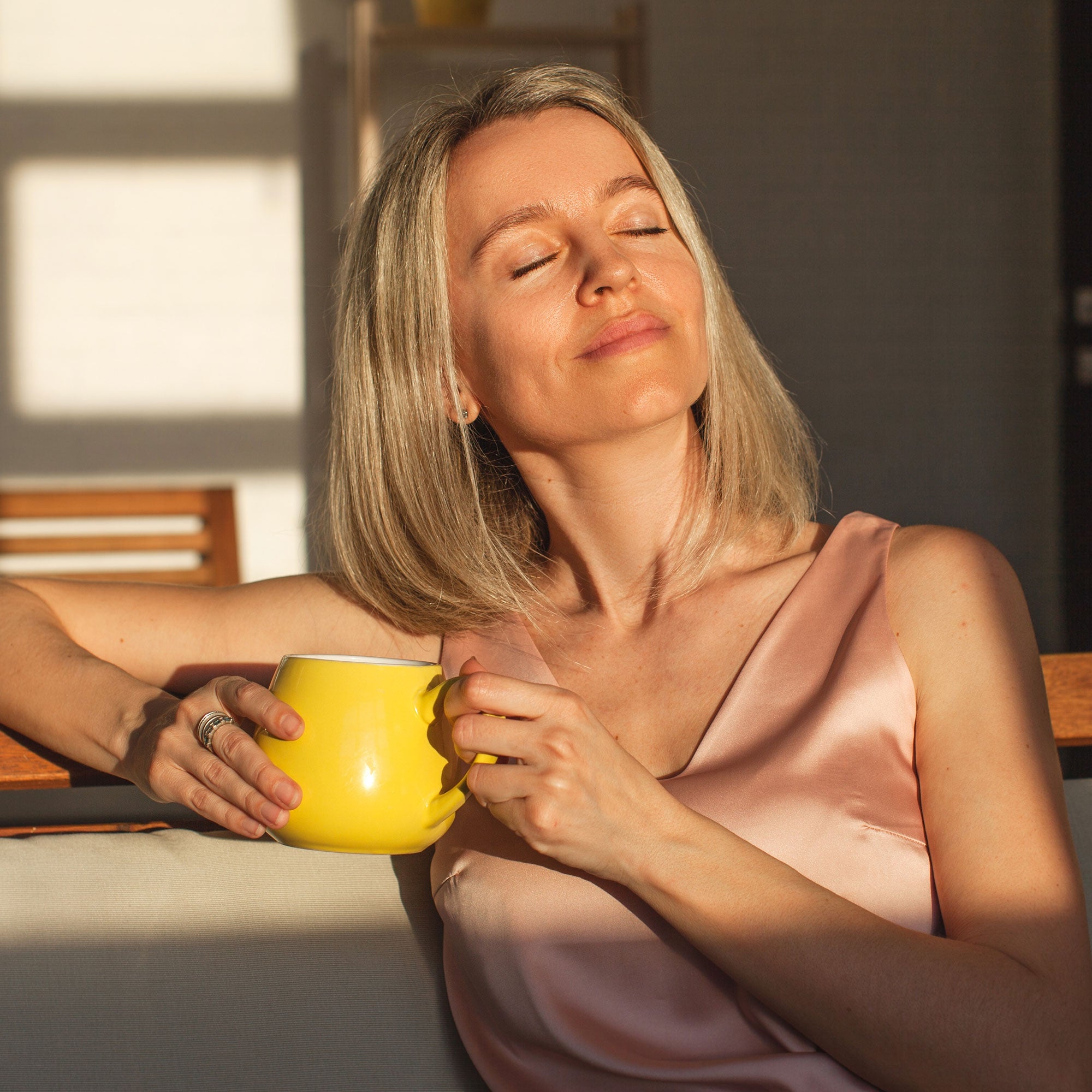 Woman holding a yellow mug with a warm glow in a softly lit room